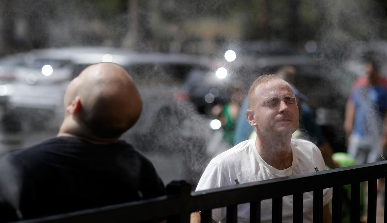 Warga mendinginkan diri dengan kabut air di sepanjang Las Vegas Strip, Amerika Serikat, Selasa (24/7). Badan Cuaca Nasional telah mengeluarkan peringatan panas ekstrem untuk lembah Las Vegas. (AP Photo/John Locher)