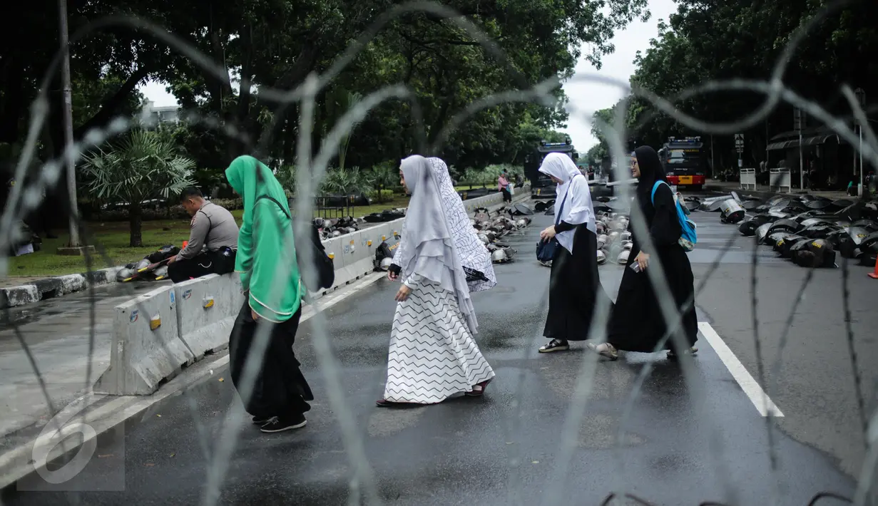Masyarakat melintasi kawat berduri saat aksi bela islam 313 di Jalan Merdeka Barat, Jakarta, Jumat (31/3). Mereka menuntut kepada Presiden Jokowi agar melaksanakan undang-undang dengan mencopot gubernur terdakwa, Ahok . (Liputan6.com/Faizal Fanani)