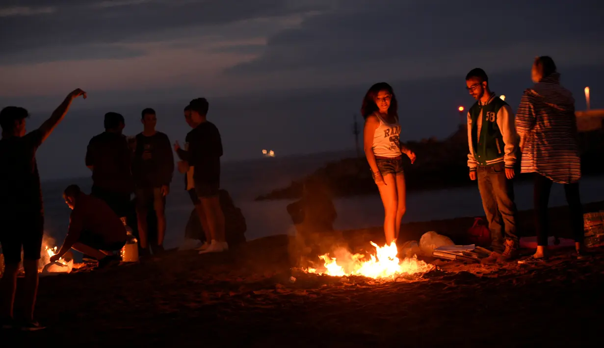 Sejumlah orang membakar barang-barang saat mengikuti tradisi malam San Juan's (Saint John) di Gijon, Spanyol, (24/6). Malam San Juan adalah upacara penyucian dimana warga membakar sejumlah benda yang sudah tidak diinginkan. (REUTERS/Eloy Alonso)