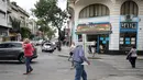 Seorang pria memegang salib berjalan di lingkungan La Boca, Buenos Aires pada 27 November 2018. La Boca berarti 'mulut', karena kedekatannya dengan sungai yang menjadikannya pelabuhan para imigran Eropa di masa lalu. (Ludovic MARIN / AFP)