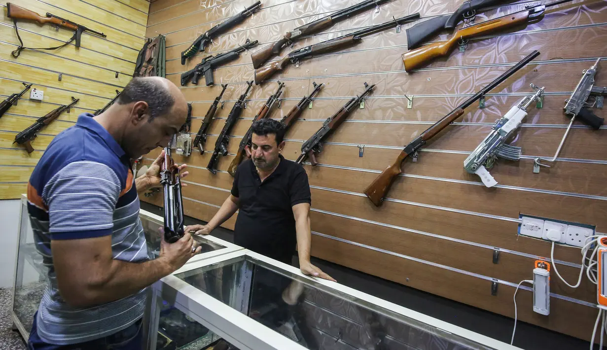 Seorang penjual, Abu Hauraa membantu pembeli memilih senapan di toko senjata berlisensi miliknya di Baghdad, Irak, 24 September 2018. Setelah pelegalan senjata api untuk orang sipil, permintaan akan senjata api semakin meningkat. (AFP/AHMAD AL-RUBAYE)
