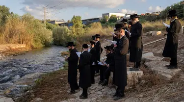 Yahudi ultraortodoks berpartisipasi dalam upacara Tashlich di tepi sungai dekat Beit Shemesh, Israel, Rabu (20/9/2023). Tashlich, yang berarti 'membuang' dalam bahasa Ibrani, adalah praktik di mana orang Yahudi pergi ke perairan besar yang mengalir dan secara simbolis 'membuang' dosa mereka dengan melemparkan sepotong roti atau makanan serupa ke dalam air. (AP Photo/Ohad Zwigenberg)