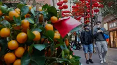 Orang-orang berjalan melewati dekorasi untuk merayakan Tahun Baru Imlek di Hong Kong, Minggu (30/1/2022). Tahun Baru China atau Imlek jatuh pada 1 Februari (AP Photo/Vincent Yu)