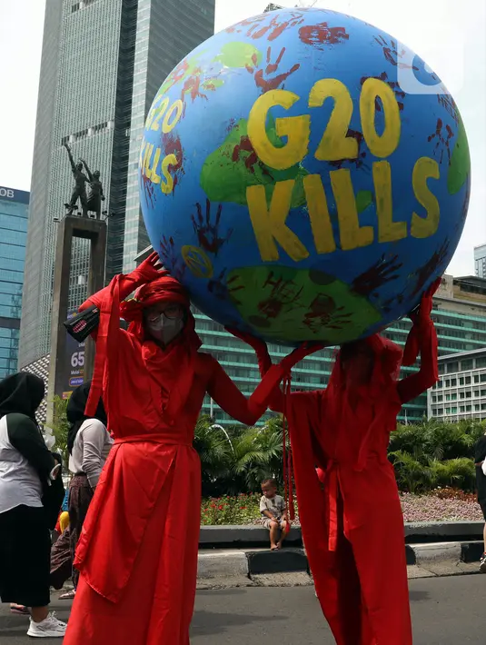 Aktivis iklim melakukan teatrikal dengan membawa bola dunia saat aksi di kawasan Bundaran Hotel Indonesia, Jakarta, Minggu (13/11/2022). Aksi yang digelar berbarengan dengan penyelenggaraan G20 ini meminta pemimpin dunia menemukan solusi bersama atas kondisi ekonomi global. (Liputan6.com/Herman Zakharia)