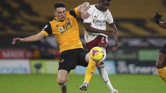Gelandang Arsenal, Bukayo Saka (kanan) berebut bola dengan bek Wolverhampton Wanderers, Max Kilman pada pekan ke-22 Liga Inggris di stadion Mollineux, Rabu (3/2/2021) dini hari WIB. Arsenal harus pulang dengan tangan hampa usai kalah 1-2 atas Wolverhampton. (Cath Ivill/Pool via AP)