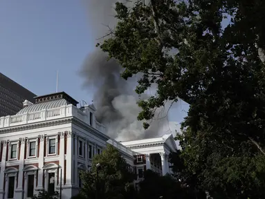 Asap mengepul dari atap sebuah gedung selama insiden kebakaran di kawasan Parlemen Afrika Selatan di Cape Town (2/2/2022). Gedung Parlemen Afrika Selatan dibakar hingga sejumlah bagiannya hancur. Presiden Cyril Ramaphosa berkata hal ini menyakiti rasa demokrasi di Afrika Selatan. (AFP/Marco Longari)