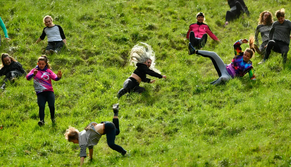 Peserta berlomba mengejar keju dalam kompetisi Cheese Rolling di Bukit Cooper, Gloucestershire, Inggris, Senin (27/5/2019). Ada lima sesi kompetisi balapan menggelindingkan keju dalam festival ini, yaitu 4 sesi untuk pria dan satu sesi untuk wanita. (Ben Birchall/PA via AP)