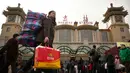Seorang wanita membawa barang bawaannya di luar Stasiun Kereta Api Beijing, China (9/2). Sambut perayaan Imlek 2018, Jutaan warga China mulai memenuhi stasiun, bandara dan jalan yang diperkirakan akan dimulai akhir pekan ini. (AP Photo/Mark Schiefelbein)