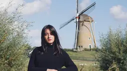 Mawar Eva tampil membawa kopernya dengan background foto bangunan kincir angin dan tak lupa tanaman hijau sebagai pemanis. Pemain film Bumi Manusia ini membagikan momennya saat traveling ke Netherlands, Belanda. (Instagram/@mawar_eva)