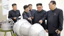 Kim Jong-un berbincang dengan para peneliti saat meninjau pembuatan bom hidrogen pada 3 September 2017. Bom ini diklaim berkekuatan hingga ratusan kiloton ini dibuat dengan berbagai komponen produksi dalam negeri. (AFP Photo/Kcna Via Kns/Str)