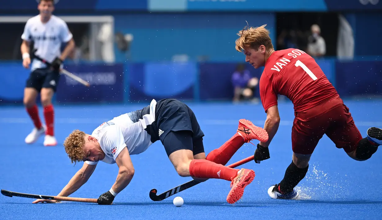 Pemain Inggris Jacob Benjamin Draper (kiri) terjatuh saat berebut bola dengan Floris Frederik Van Son dari Kanada dalam pertandingan hoki lapangan grup B putra Olimpiade Tokyo 2020, di Oi Hockey Stadium di Tokyo pada 26 Juli 2021. (Ina Fassbender / AFP)