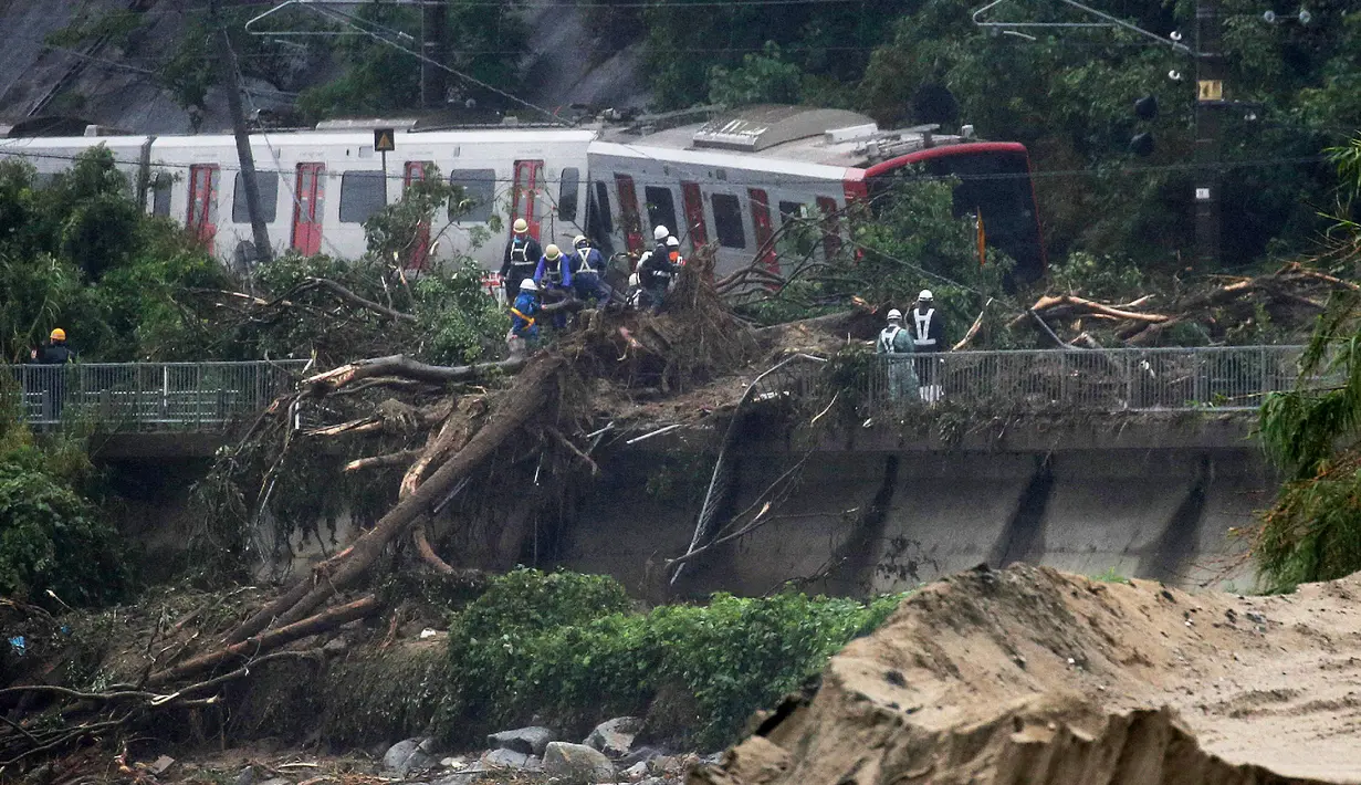 Petugas darurat melakukan penanganan setelah kereta berhenti karena longsor yang melanda Kota Karatsu, Prefektur Saga, Jepang, Sabtu (7/7). Aparat telah melaksanakan proses penyelamatan bagi warga yang terdampak parah. (STR/JIJI PRESS/AFP)