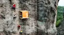 Sejumlah orang memanjat tebing melewati toko serba ada yang menempel di dinding tebing di Pingjiang di provinsi Hunan, China (25/4). Toko ini menjual minuman dan makanan untuk para pemanjat tebing yang melintas. (AFP Photo/China Out)