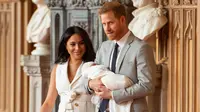 Pangeran Harry dan Meghan Markle berjalan membawa bayi laki-lakinya yang baru lahir di St George's Hall di Windsor Castle di Windsor, London (8/5/2019). Pangeran Harry menyatakan bahwa dia dan Meghan Markle masih memikirkan nama anak mereka. (AFP Photo/Dominic Lipinski)