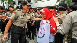 Seorang polwan berdialog dengan pendemo agar tidak menutup akses jalan ketika menggelar demonstrasi di depan gedung Kemenkes, Jakarta, Rabu (4/5). Para bidan desa berdemo menuntut diangkat menjadi pegawai tetap tanpa syarat.  (Liputan6.com/Yoppy Renato)