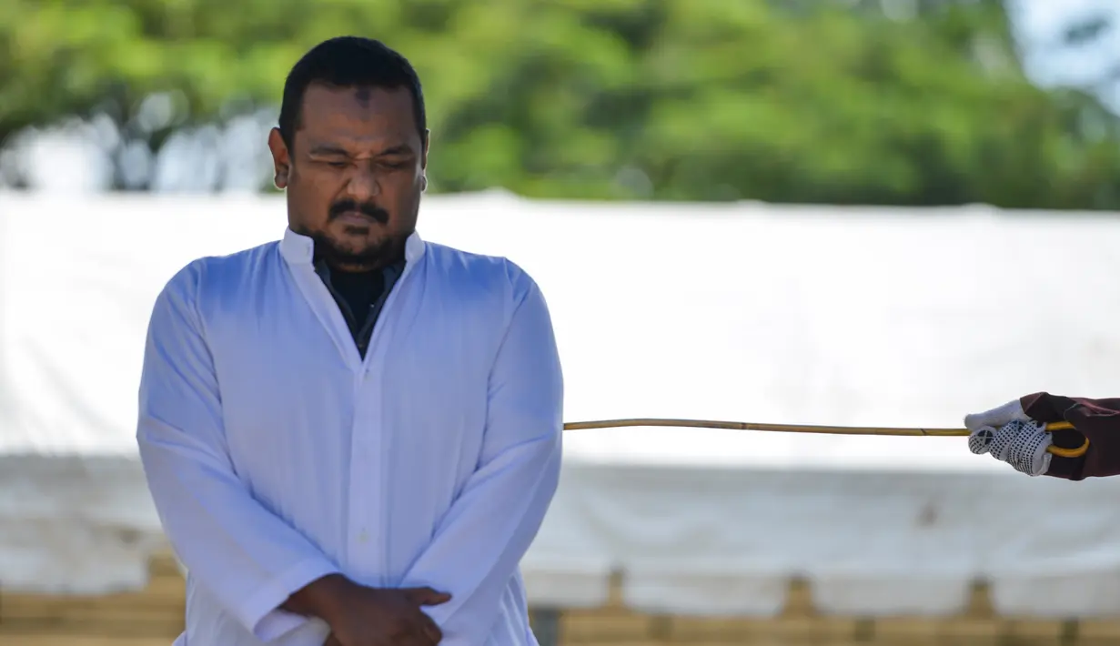 Ekspresi manajer hotel, Firman Syahaputra (34) saat mendapat hukum cambuk setelah tertangkap mesum di Banda Aceh, Senin (29/10). Eksekusi cambuk terhadap Firman dan pasangannya digelar di halaman Masjid Baitul Musyahadah. (Chaideer Mahyuddin/AFP)
