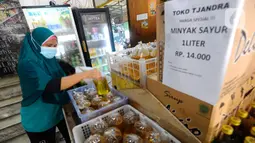 Warga membeli minyak goreng curah di Toko Tjandra, Cinere, depok, Jumat (03/06/2022). Paska dicabutnya kebijakan subsidi minyak goreng curah, pembeli minyak goreng curah di pasaran diwajibkan menyertakan kartu tanda penduduk (KTP) dengan maksimal 1 ktp untuk 2 liter minyak goreng curah seharga Rp 14.000/liter. (merdeka.com/Arie Basuki)