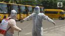 Petugas disemprot disinfektan sebelum menjemput pasien Covid-19 menggunakan bus sekolah di Puskesmas Jatinegara, Jakarta, Selasa (22/9/2020). Bus sekolah Pemprov DKI kini dialihfungsikan menjadi kendaraan untuk mengantar pasien Covid-19 berstatus OTG menuju Wisma Atlet. (merdeka.com/Imam Buhori)