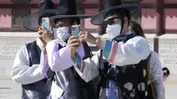 Para pria yang mengenakan masker sebagai tindakan pencegahan terhadap virus corona mengambil foto saat mereka berkunjung untuk merayakan liburan Chuseok, Hari Thanksgiving versi Korea, di Istana Gyeongbok di Seoul, Korea Selatan, Rabu (22/9/2021). ( AP Photo/Ahn Young-joon)