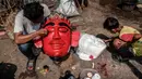 Seorang pria melukis topeng baru untuk ondel-ondel di Jakarta pada Minggu 4 Mei 2025. (Yasuyoshi CHIBA/AFP)