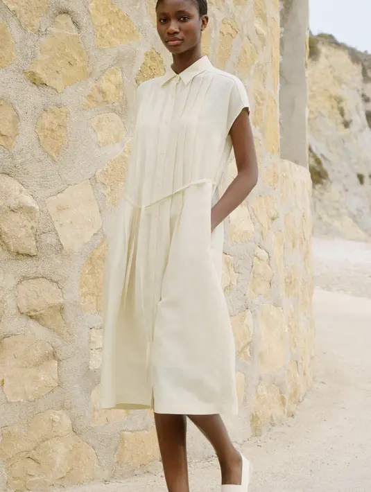 Selanjutnya, Gaun Kemeja Linen Blend dengan lengan pendek hadir dengan tambahan detail tali di pinggang, memungkinkan penampilan Sahabat Fimela bisa beralih antara kasual atau smart casual sesuai kebutuhan. [Foto: Dokumen/UNIQLO X COMPTOIR DES COTONNIERS]
