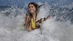 Mariana Rojas dan anjingnya bermain ombak di lepas pantai Los Angeles setelah dibuka kembali di La Guaira, Venezuela, Jumat (23/10/2020). Pemberlakuan lockdown yang ketat akibat COVID-19 memaksa penutupan pantai di seluruh negeri pada Maret lalu dan dibuka kembali minggu ini. (AP/Matias Delacroix)