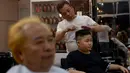 Le Phuc Hai, 66 tahun (kiri) dan To Gia Huy , 9 tahun, setelah rambut mereka dipangkas dengan gaya pemimpin Korea Utara Kim Jong-un dan Presiden Amerika Serikat, Donald Trump di sebuah salon di Hanoi, Vietnam, 19 Februari 2019. (AP/Hau Dinh)