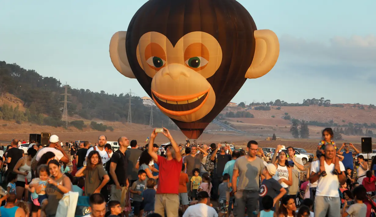 Sejumlah pengunjung menyaksikan Festival Balon Udara Gilboa di dekat Kibbutz Ein Harod, Lembah Jizreel, Israel (4/8). Acara ini juga dimeriahkan dengan pertunjukan paragliders, paramotor dan karya para seniman udara. (AFP Photo/Manahem Kahana)