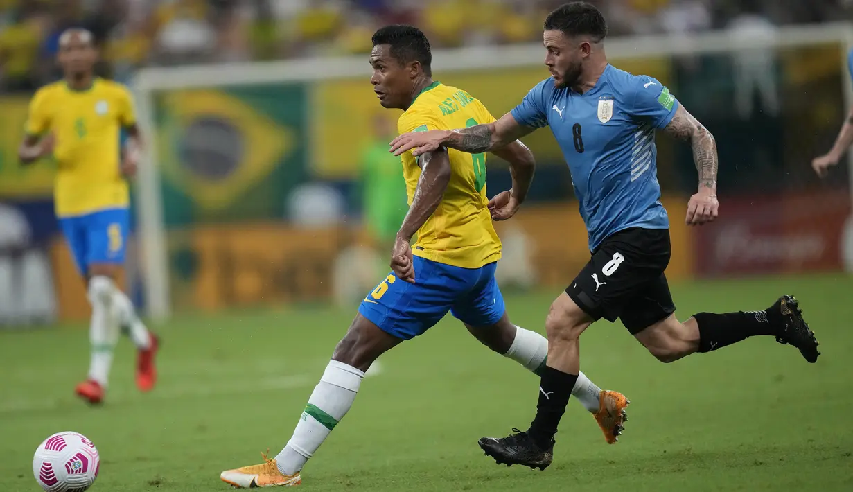 Pemain Brasil Alex Sandro (kiri) berebut bola dengan pemain Uruguay Nahitan Nandez pada pertandingan kualifikasi Piala Dunia 2022 di Arena da Amazonia, Manaus, Brasil, Kamis (14/10/2021). Brasil menang 4-1. (AP Photo/Andre Penner)