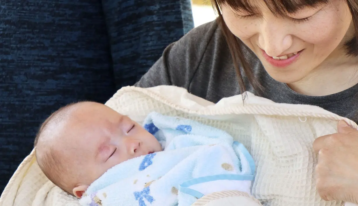 Ryusuke Sekino, bayi laki-laki terkecil di dunia digendong oleh ibunya Toshiko Sekino di Azumino, Prefektur Nagano, Jepang, Sabtu (20/4). Bayi yang lahir saat usia kandungan baru 24 minggu lima hari itu diklaim sebagai bayi laki-laki terkecil di dunia. (Kyodo via REUTERS)