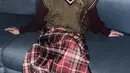 Ghea cosplay menjadi Betty La Fea dengan mengenakan knit vest coklat dipadukan inner kemeja lengan panjang dan rok tartan merah. Kacamata besar juga dikenakan sebagai ciri khas. [@gheaindrawari]