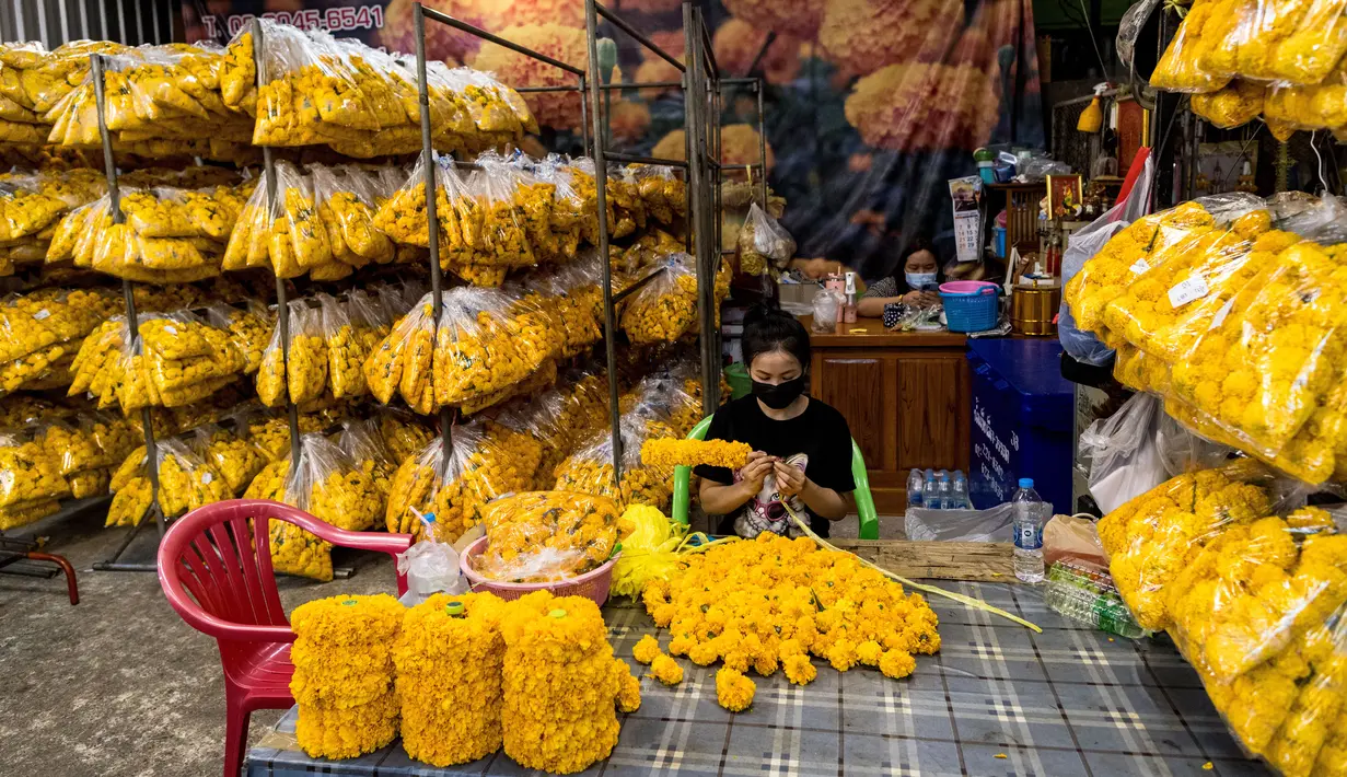 Seorang wanita membuat karangan bunga marigold menjelang Loy Krathong di pasar bunga Pak Khlong Talat, Bangkok, Kamis (18/11/2021). Bulan November ini Thailand akan mengadakan festival Loy Krathong di mana warga menghanyutkan keranjang berisi bunga dan lilin di sungai atau danau. (Jack TAYLOR/AFP)