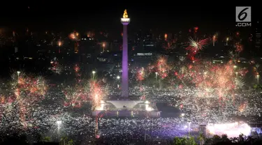 Kembang api menghiasi malam pergantian tahun baru 2018 di kawasan silang Monumen Nasional (Monas), Jakarta, Senin (1/1/2018). Monas menjadi salah satu lokasi pilihan Warga Jakarta untuk merayakan malam pergantian tahun. (Liputan6.com/Johan Tallo)