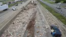 Ratusan pizza beku berserakan di Jalan Raya Arkansas, Amerika Serikat, 9 Agustus 2017. Kejadian disebabkan truk pembawa pizza beku dengan 18 roda kehilangan kendali setelah melintasi jembatan dan terbalik. (Arkansas Department of Transportation via AP)