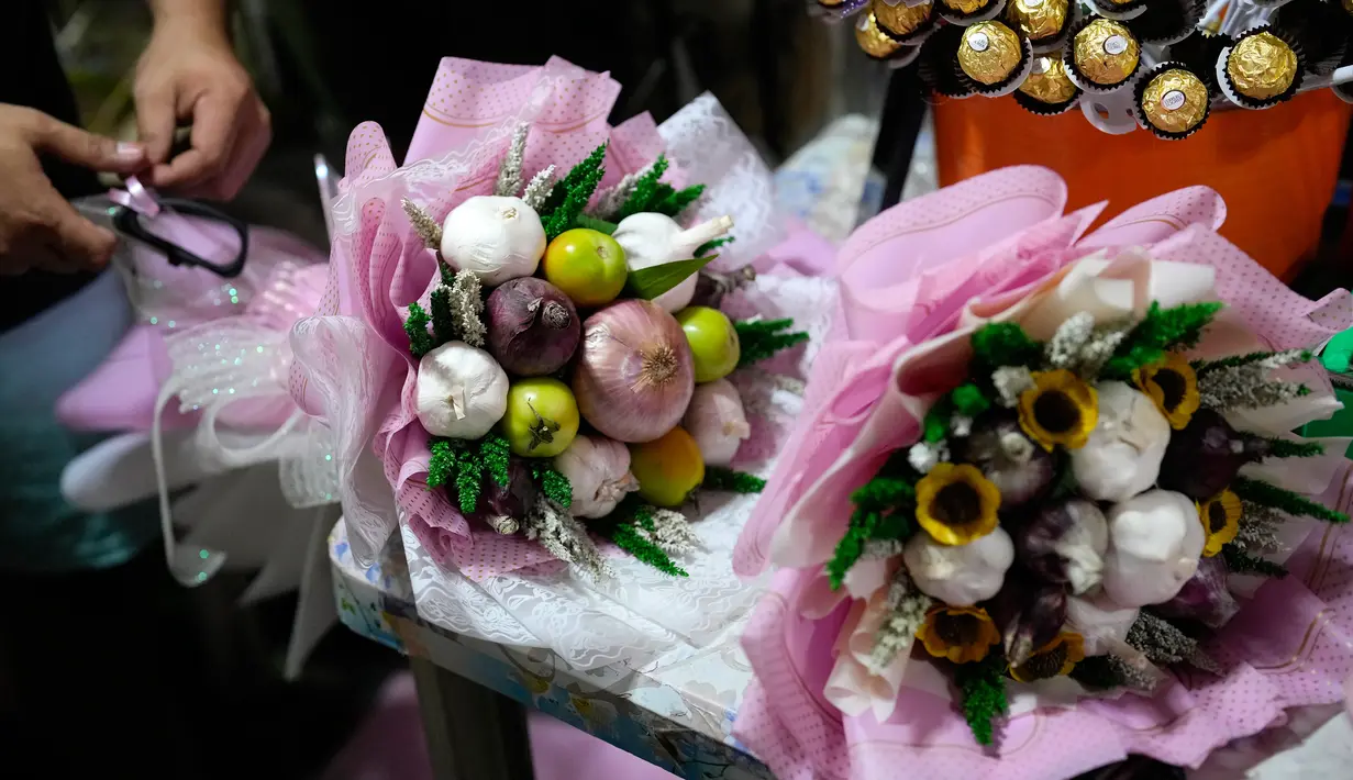 Karangan bunga yang terbuat dari bawang merah, tomat, dan bawang putih dipajang di pasar bunga di Manila, Filipina, Senin (13/2/2023). Dia menjual karangan bunga dari 500 - 1.500 peso (USD 9 - USD27) tergantung pada pilihan bawang merah, jahe, bawang putih, tomat dan cabai merah atau hijau. (AP Photo/Aaron Favila)