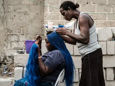 Seorang wanita saat dikepang rambutnya di pemukiman informal Elechi Phase 3 di Port Harcourt, Nigeria selatan (14/2). Nigeria akan mengadakan pemilihan presiden dan parlemen pada tanggal 16 Februari 2019. (AFP Photo/Yasuyoshi Chiba)