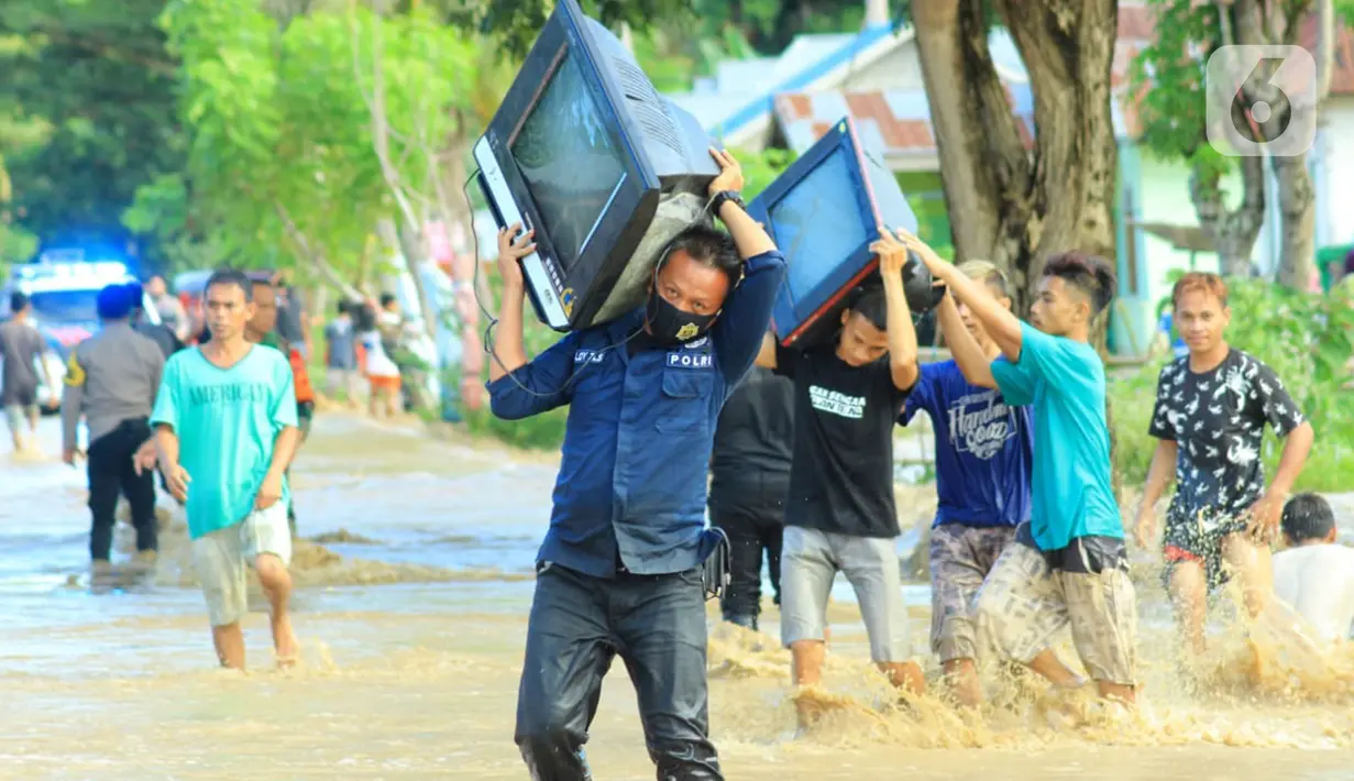 Warga membawa barang miliknya saat banjir bandang  di Kabupaten Bone Bolango, Gorontalo (11/6/2020). Data sementara yang diterima dari BPBD Kabupaten Bone Bolango sekitar 1.078 kepala keluarga serta 5.407 jiwa terdampak banjir bandang. (Liputan.com/Arfandi Ibrahim)