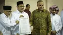 Menag Lukman Hakim Saifuddin menunjukan surat yang usai ditanda tangani saat meresmikan pemajangan potongan Kiswah (kain penutup Kakbah) hadiah dari Raja Salman bin Abdulaziz Al Saud di Masjid Istiqlal, Jakarta, Jumat (10/3). (Liputan6.com/Faizal Fanani)