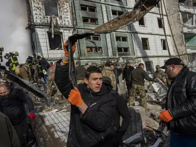 Petugas memindahkan puing-puing setelah serangan Rusia di sebuah bangunan tempat tinggal di Uman, Ukraina tengah, Jumat, 28 April 2023. (AP Photo/Bernat Armangue)
