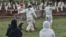 Petugas mengenakan APD lengkap membawa peti jenazah untuk dimakamkam dengan protokol Covid-19 di TPU Bambu Apus, Jakarta, Kamis (28/1/2021). Pemprov DKI menyiapkan 6 lokasi baru untuk pemakaman jenazah pasien Covid-19 dengan total kapasitas 17.900 petak makam. (merdeka.com/Iqbal S Nugroho)