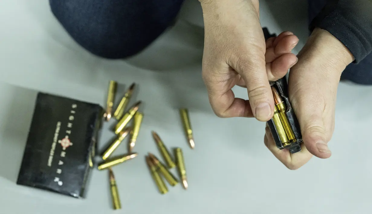 Seorang wanita mengisi amunisi untuk senapan serbu Kalashnikov selama pelatihan di Kharkiv, Ukraina (30/1/2022). Beberapa orang di kota terbesar kedua di Ukraina bersiap untuk melawan jika Rusia menyerang. (AP Photo/Evgeniy Maloletka)