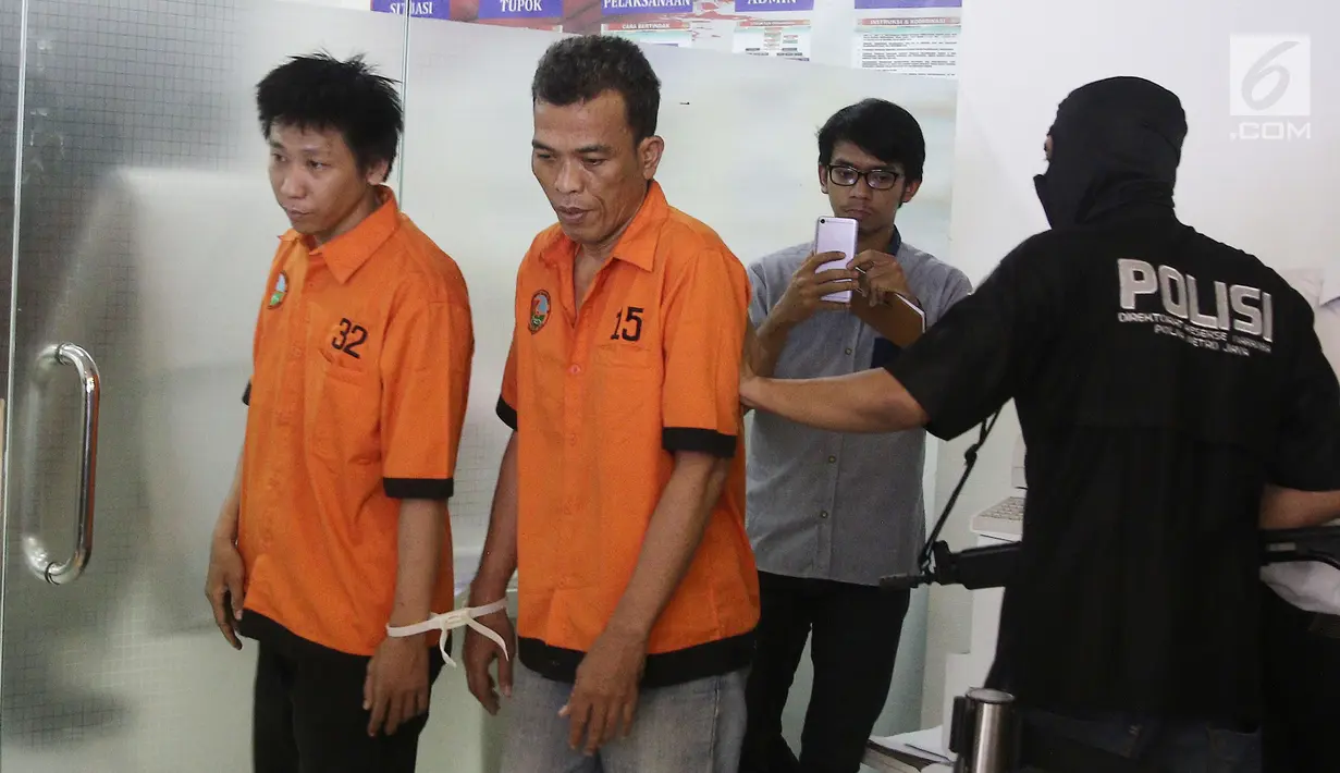 Petugas menggiring dua tersangka kepemilikan 20 ribu happy five di Polda Metro Jaya, Jakarta, Senin (27/8). Pengedar menyamar sebagai driver ojek online (ojol) saat melakukan aksinya. (Liputan6.com/Herman Zakharia)