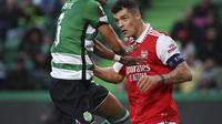 Bek Sporting CP, Jerry St. Juste (kiri) berebut bola dengan gelandang Arsenal asal Swiss Granit Xhaka  dalam laga leg pertama babak 16 besar Liga Europa 2022-2023 di Estadio Jose Alvalade, Jumat (10/3/2023) dini hari WIB. Arsenal akan meladeni Sporting di Emirates Stadium dalam duel leg kedua Liga Europa pekan depan. (Photo by FILIPE AMORIM / AFP)