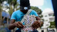 Wilmer Rojas (25) saat membuat tas dari lembaran mata uang Bolivar di Caracas, Venezuela, 30 Januari 2018. Lembaran uang tersebut kini tidak lagi menjadi alat jual beli, melainkan bahan untuk membuat kerajinan tangan. (AFP Photo/Federico Parra)