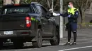 Petugas polisi menghentikan mobil untuk pemeriksaan izin selama tahap empat penguncian kota yang ketat karena wabah COVID-19 di Melbourne (11/8/2020). Negara bagian Victoria melaporkan 19 kematian akibat virus corona pada 11 Agustus. (AFP/William West)