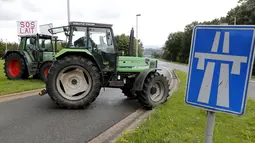 Sebuah traktor milik peternak sapi perah memblokade jalan tol atau jalan bebas hambatan saat melakukan aksi protes di Battice, Belgia, Kamis (30/7/2015). Aksi protes tersebut berkaitan dengan rendahnya harga jual susu. (REUTERS/Francois Lenoir)