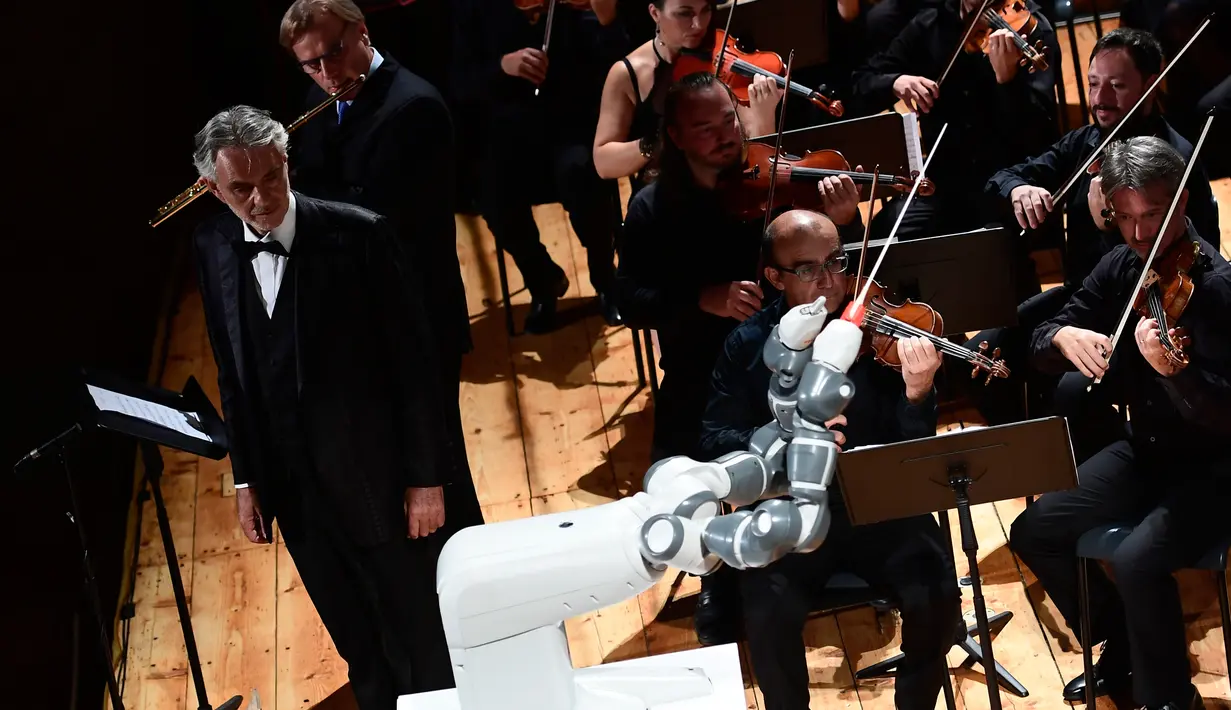 Robot YuMi saat tampil untuk pertama kalinya dalam konser Lucca Philharmonic Orchestra bersama Flutist Italia Andrea Griminelli (kedua kiri) dan penyanyi tenor Italia Andrea Bocelli di The Teatro Verdi di Pisa, Italia (12/9). (AFP Photo/Miguel Medina)