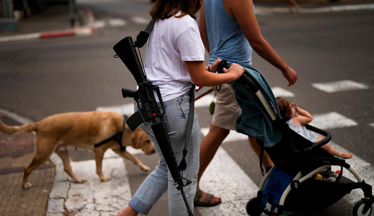 Yehudit, seorang tentara Israel yang sedang tidak bertugas, mendorong troli bersama keponakannya saat mereka berjalan-jalan di pusat Tel Aviv, Israel, Jumat (27/10/2023). (AP Photo/Francisco Seco)