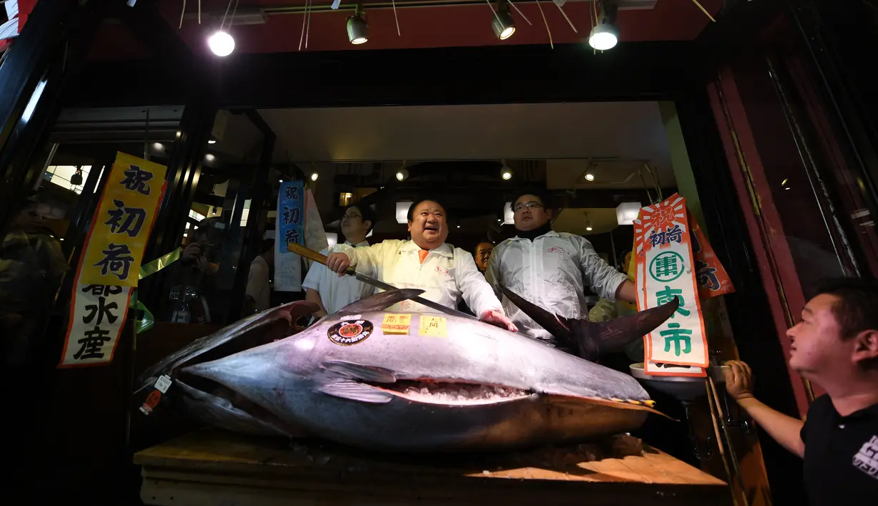 CEO Sushi Zanmai, Kiyoshi Kimura berpose dengan ikan tuna seharga 74,2 juta yen (212 kilogram) di depan restorannya, dekat pasar ikan Tsukiji, Tokyo, Kamis (5/1). Kimura memenangkan ikan itu pada lelang tuna pertama tahun 2017. (TOSHIFUMI KITAMURA/AFP)
