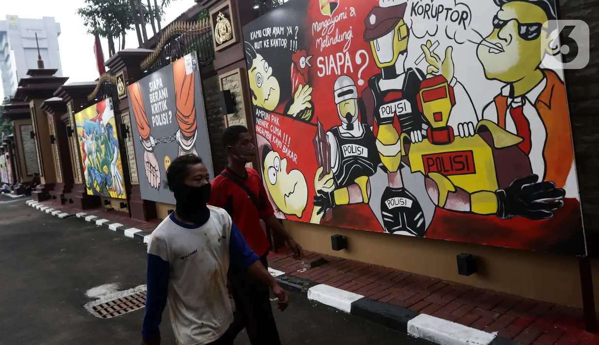 Warga melintas di depan mural berisi kritik terhadap kinerja polisi di Lapangan Bhayangkara Mabes Polri, Jakarta, Minggu (31/10/2021). Lomba mural 2021 Piala Kapolri menampilkan sejumlah karya berisi kritik terhadap polisi yang dituangkan pada media triplek. (Liputan6.com/Helmi Fithriansyah)